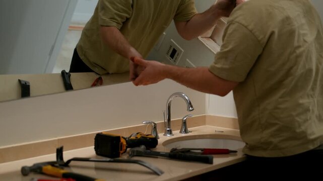 Construction workers remove large mirror in the bathroom during renovation. Interior demolition, removal of old materials, home improvement