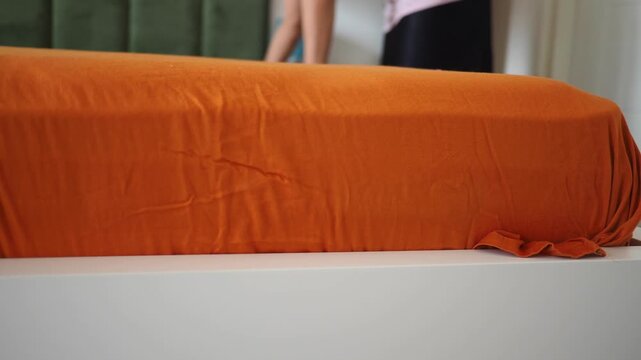 Woman carefully placing a fitted bedsheet on a comfortable mattress in a modern bedroom.