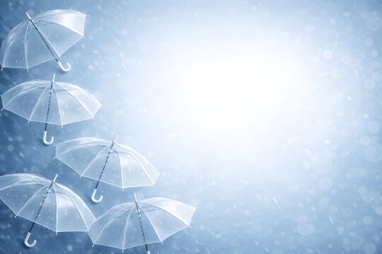 Transparent umbrellas in rain with soft blue background and copy space
