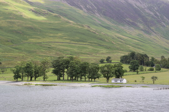 White cottage on a lake shore surrounded by hills
