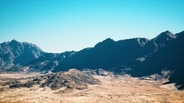 sunlit rocky mountain range, clear sky. aerial panorama of arid desert basin with rugged ridges and sunlit plateaus crisp blue tones create cinematic mood