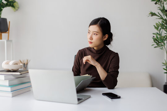 Asian woman working from home thinking about business strategy