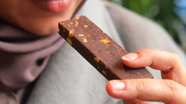 Woman holding healthy protein energy bar with nuts outdoors close up cinematic shot motion.