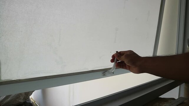 Detailed footage capturing a person&rsquo;s hand lifting and opening frosted glass window panel with soft light passing through the opaque surface in an indoor setting