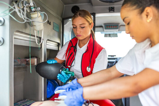 Emergency medical team performing CPR and using resuscitator bag on patient in ambulance. Professional paramedics providing life-saving treatment. Healthcare and medicine concept, critical rescue.