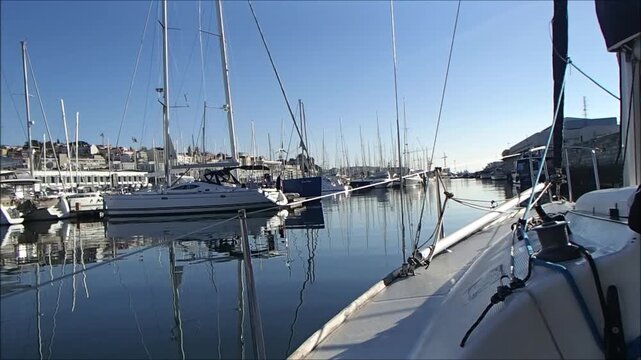 Sailboats docked in a calm harbor under a clear blue sky with reflections