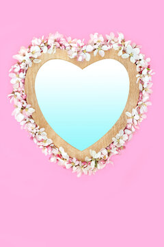Spring apple blossom heart shape wreath decoration, wooden frame on pink, gradient blue fill. Symbol of love for Mothers Day, Beltane, Valentines, birthday.