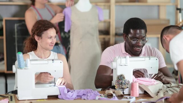 Diverse group of students, women and men, participating dressmaking class, focused on learning practical sewing techniques, constructing and adjusting garments in tailor workshop