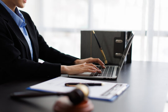 Legal professional typing on laptop with gavel and document