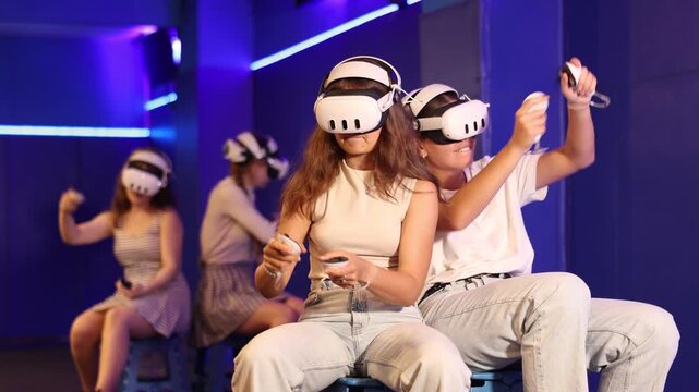 Two young girls in VR googles intensely competing in team-based virtual reality game, showcasing excitement and engagement in a futuristic gaming environment