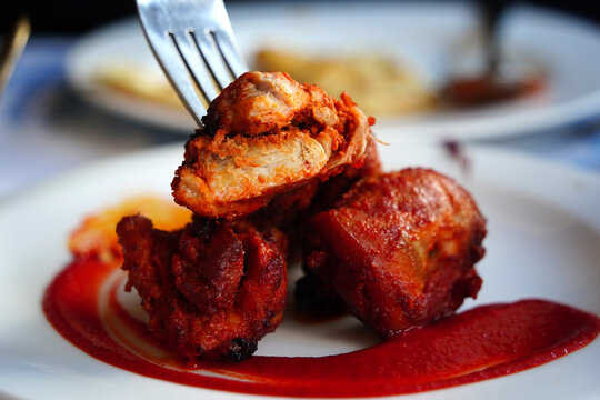 Authentic Indian Chicken Tikka served with spicy red sauce on a white plate.