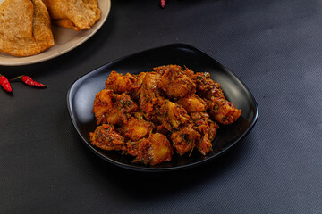 Traditional Indian potato and vegetable curry (Aloo Sabzi) served on a plate with fresh chilis.