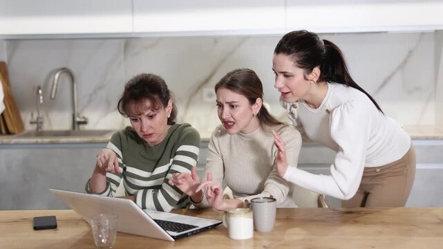 Joyful middle-aged women gloating over having won a prize sitting at notebook in the kitchen
