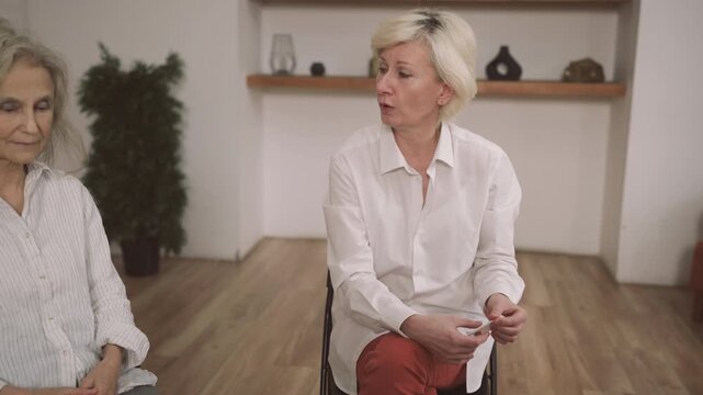 Portrait of senior woman in office of psychologist, vertical shot, female client speaking about life problems. Group therapy and support for divorced aged women, emotions and feelings, psychology
