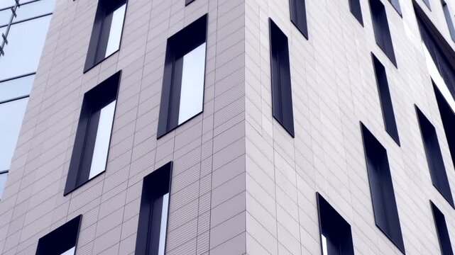 Low angle view of modern glass facade building with rhythmic window patterns and geometric architecture.