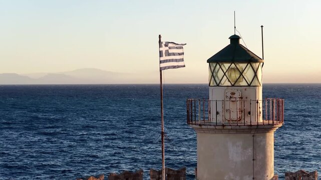 Rodos lighthouse with greek flag at golden hour