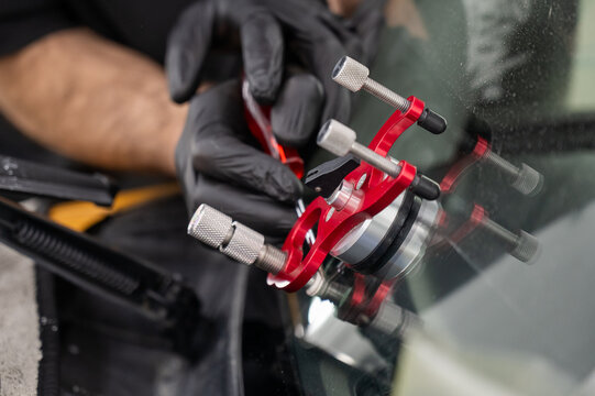 A technician injects resin into a windshield crack. 