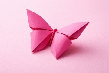 Delicate pink origami butterfly artfully crafted on a soft pastel background