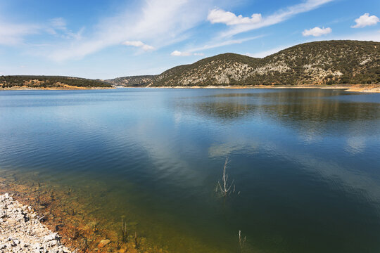 Serene mountain lake with blue reflections and Mediterranean hills under a clear sky