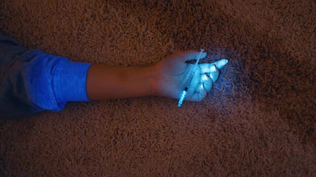 Forensic Investigator Using UV Light on a Hand Holding a Syringe
