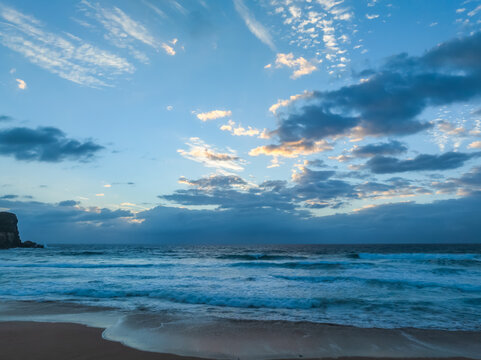 Seaside Sunrise with rolling waves and rain clouds