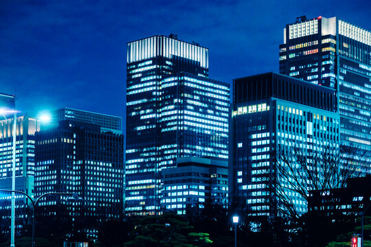 Illuminated skyscrapers in Tokyo business district with a cyber-blue aesthetic.