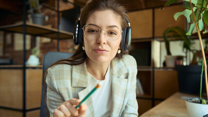 Woman with headphones pointing and explaining during online coaching session. Concept of instruction, guidance, remote learning, business coaching, and communication.