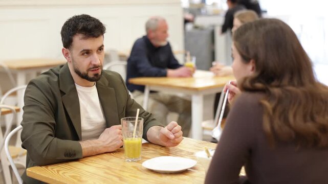 Girl in cafe spend time with guy, has nice conversation, work or romantic meeting dating. Cozy atmosphere of cafe, meeting place for friend, business partner, relative