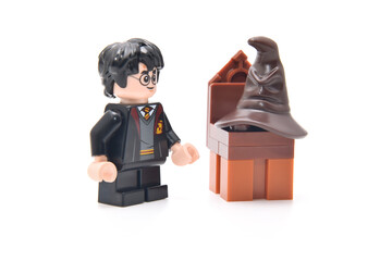 Naklejka premium Lego minifigure of Harry Potter and speaking hat on a brown chair. Editorial illustrative image of famous fantasy