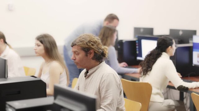  Adult man using computer for work in coworking space with team