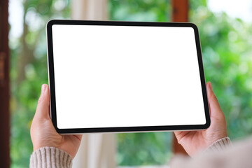 Mockup image of a woman holding digital tablet with blank white desktop screen in tropical style home © Farknot Architect