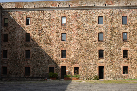 Interior view of the courtyard of the Medieval Fortress with Stone Arches of Priamar in Savona, Liguria, Italy. Close-up of an ancient fortified courtyard with a rustic stone arched gallery, medieval