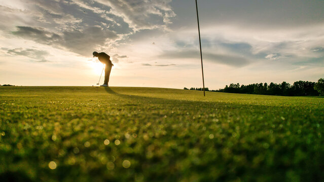 Professional young male golfer swings his club on scenic golf course. 
