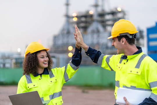 Caucasian male and Latina female engineers making high five outdoors. 