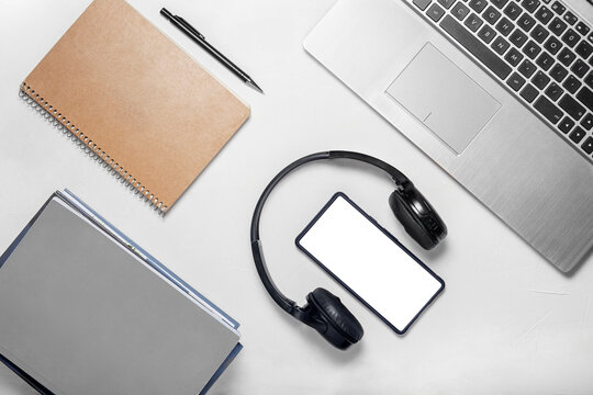 Flat lay of laptop, smartphone, headphones and stationery on white background