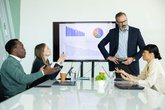 Diverse business team having a tense meeting, discussing market analysis and sales strategy after reviewing a declining performance report