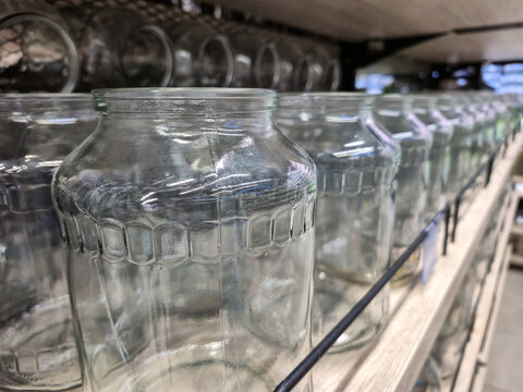 Row of empty glass jars displayed on a store shelf for sale