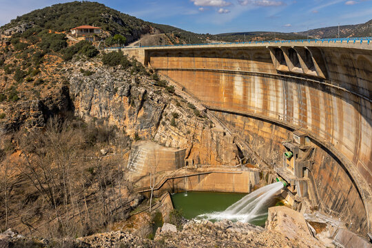 Large Curved Dam with Water Discharge into a Rocky Canyon and Mountainous Landscape