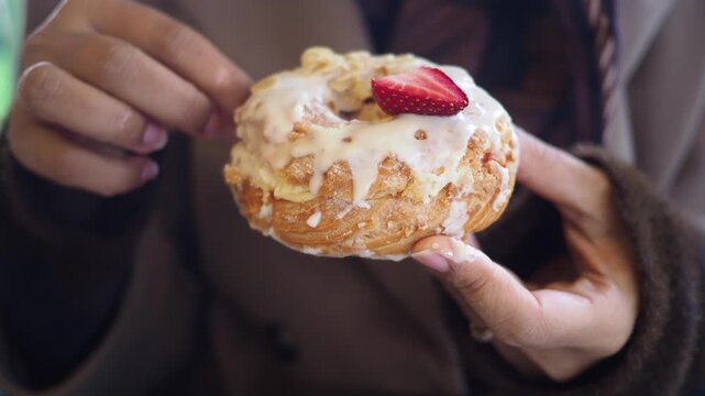 Close up shot of person showing cronut, a croissant doughnut hybrid dessert with topping.