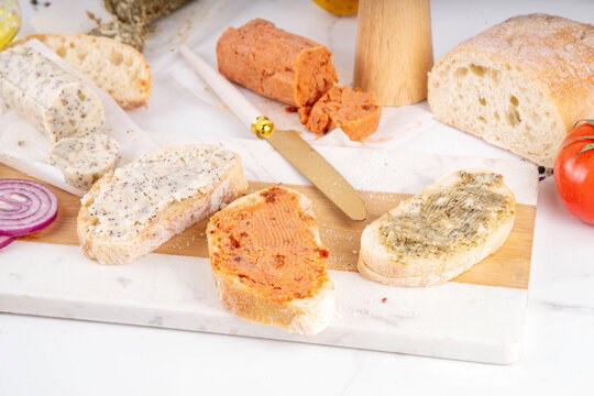 Steak butter, or Compound butter for cooking and sandwiches. Different homemade butter with herbs, spices, garlic, citrus zest, tomatoes, on white marble kitchen table