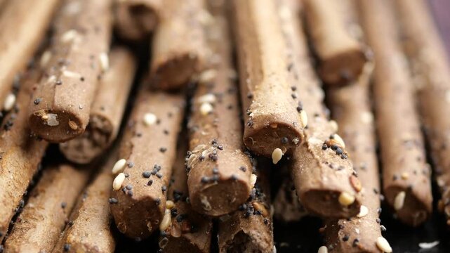 Close up of chocolate breadsticks with sesame seeds in motion.