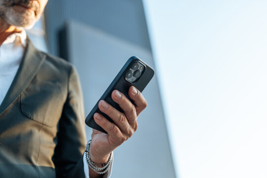 Professional businessman holding smartphone connecting online outdoors