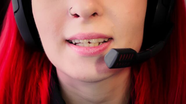 Closeup view of female speaker using high quality microphone for clear communication. Mouth of Caucasian lady with headset showing nose piercing and red hair talks with warm tone and clear diction