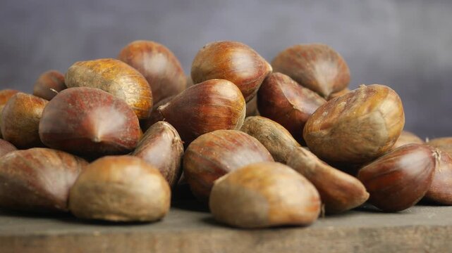 Pile of ripe chestnuts on rustic wooden surface, natural food ingredient, autumn harvest close-up.