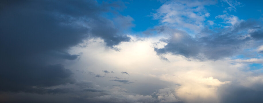 Contrasting sky with dark storm clouds and gap of blue sky with white clouds in panoramic composition