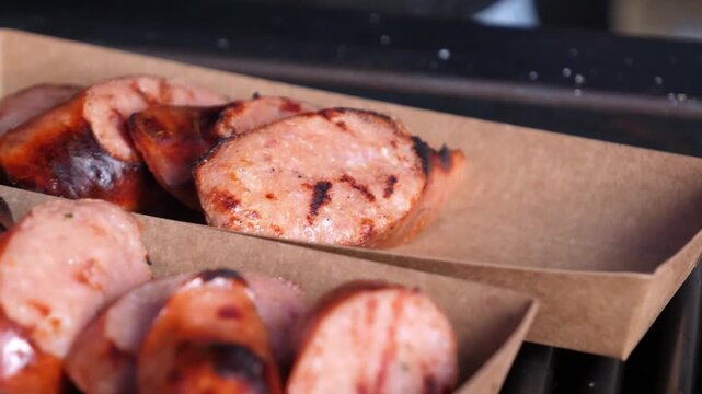 A mouthwatering, close-up shot of juicy, browned sausages being sliced and served. The footage highlights the sizzling texture and savory steam, perfect for food, BBQ, and culinary-themed content.