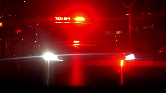 Police patrol car with flashing red and white emergency lights at night. Visible "Police" text on lightbar. Cinematic law enforcement response and public safety concept.