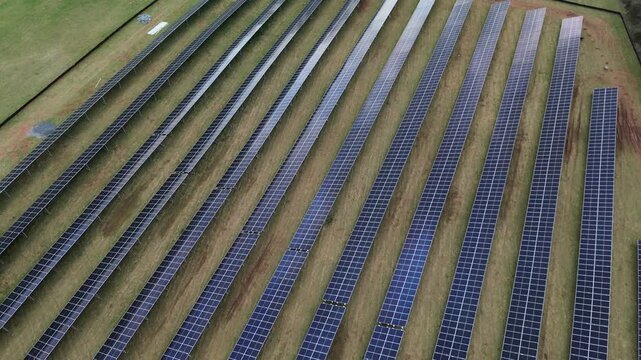 Maintained solar rows align near Creamery Road within Emmitsburg industrial corridor. Clean reflective surfaces, trimmed grass lanes and subtle soil patches create orderly geometric textures, MD