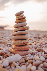 Stack of balanced zen stones on a pebble beach at sunset