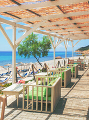 Modern beach bar terrace with wooden pergola and sea view in summer